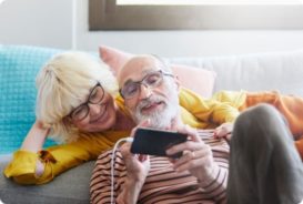 A man and woman smiling watching something on his phone